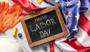 An image of a wooden chalk board with Happy Labor Day written on it.